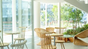 Een modern interieur met rieten meubels, grote ramen en uitzicht op groen.