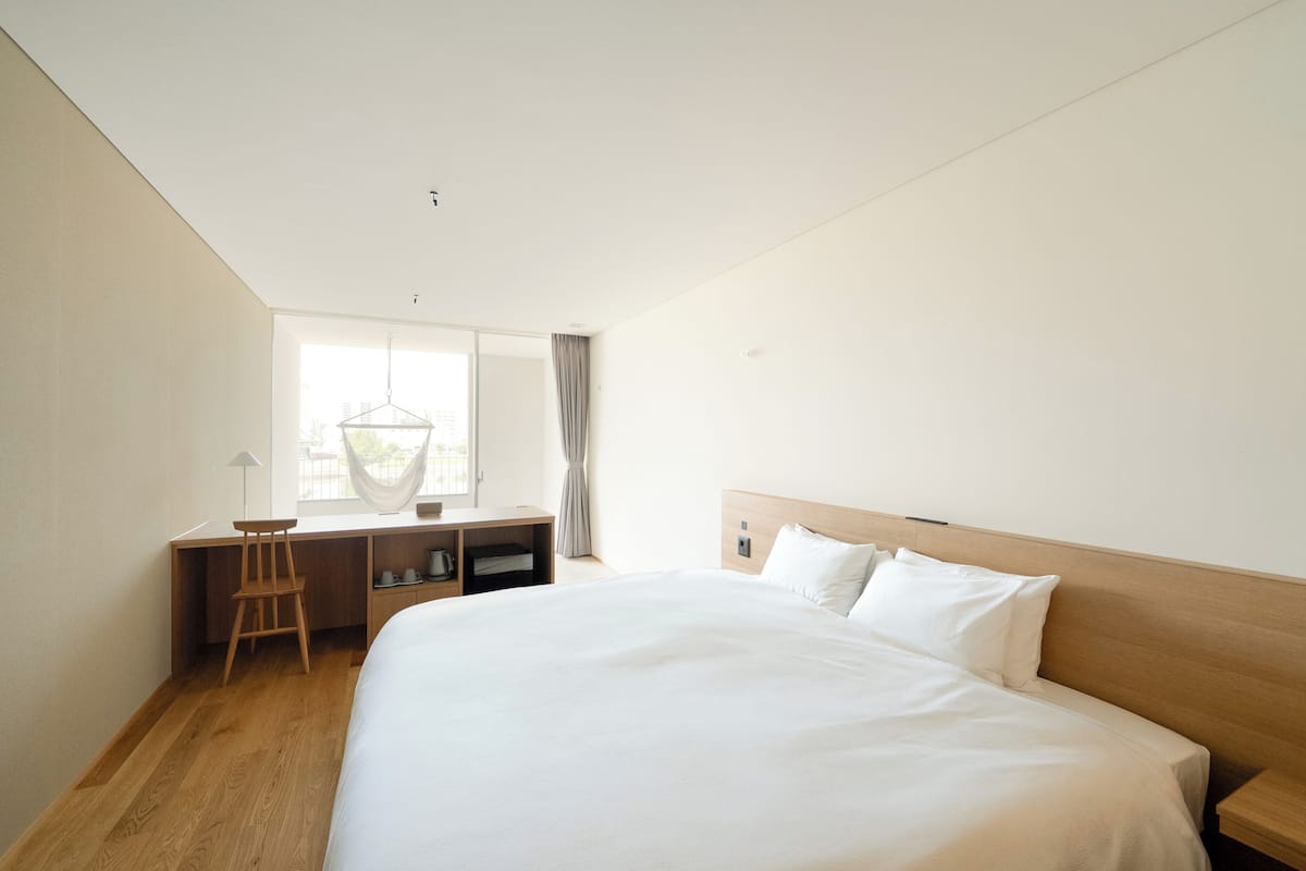 Une chambre dâhĂŽtel moderne, dotĂ©e dâun grand lit, dâun bureau et dâune chaise.