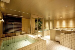 Een moderne badkamer met een groot bad, een aparte douche en een toilet met glazen afscheiding.