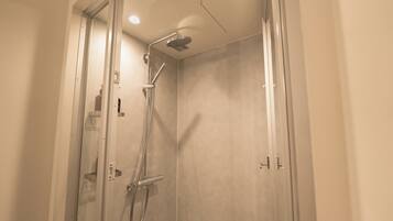Une douche moderne dotée d’un pommeau de douche à main et d’une douche à pluie fixée au plafond.
