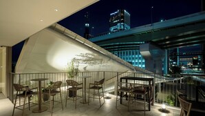 Una terrazza sul tetto con posti a sedere all'aperto e vista sullo skyline della città di notte.