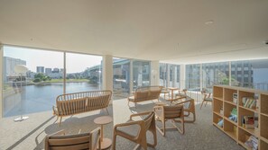 A modern interior with large windows, wooden furniture, and a view of a river and buildings. - SETRE CANAL NAGOYA (Nagoya)