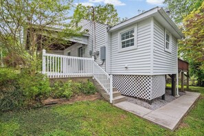 A two-story house with a white exterior, a front porch with a white railing, and a small deck area. - Ideal Location! Peaceful and Comfy 1 bed/1 bath (Clarksville)