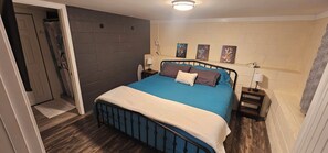 A bedroom with a bed, bedside tables, a door, and a wall with three paintings. - Ideal Location! Peaceful and Comfy 1 bed/1 bath (Clarksville)