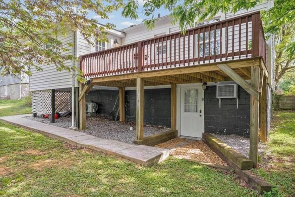 A covered patio area with a wooden deck, a door, and a small enclosed space with a window.