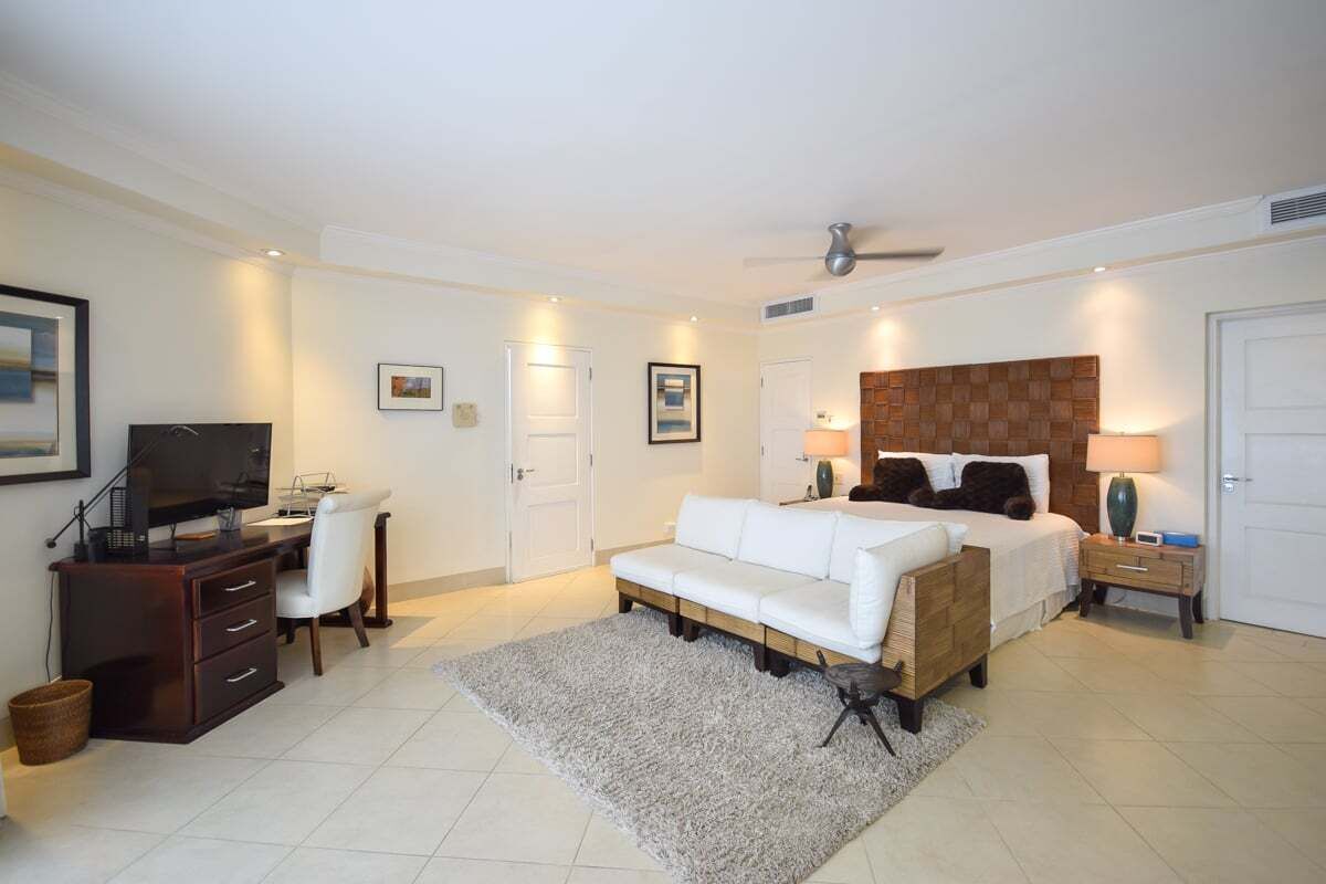 A bedroom with a bed, desk, chair, and TV.