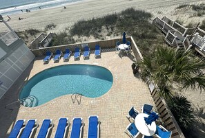 Ein Poolbereich mit blauen Liegestühlen, einem kleinen Pool und einer Holzterrasse mit Blick auf den Strand.