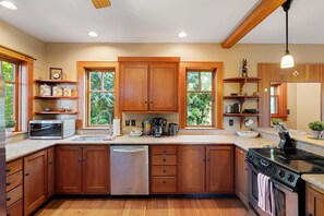 Una cocina con armarios de madera, lavavajillas, horno y cafetera.