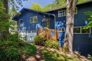 A two-story house with a blue exterior, a wooden staircase, and a garden area.