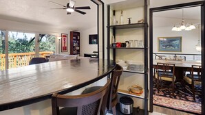 Un espace repas comprenant une grande table, des chaises, un ventilateur de plafond et une vue sur l’extérieur.