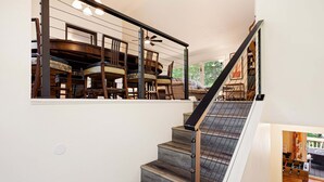 Un escalier au design moderne, un coin repas avec des meubles en bois et une vue dégagée sur l’extérieur.