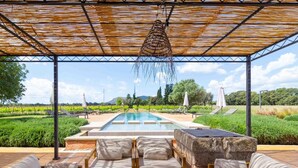 Un espace extérieur abrité comprenant une piscine, des chaises longues et une table en pierre.
