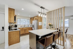 Une cuisine moderne avec des meubles en bois, un Ăźlot central et un coin repas avec des chaises.
