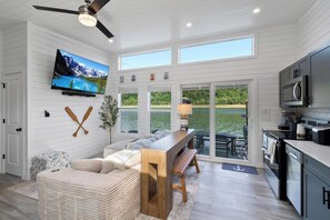 Una cocina moderna con televisor, muebles de madera y vista a un lago.