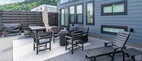 Un patio con mobiliario exterior, una parrilla cubierta y un edificio con un cartel de 'Welcome to Lake'.