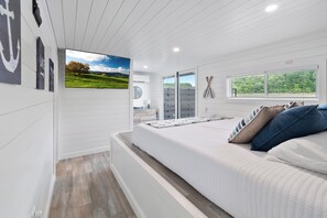 Un dormitorio con cama, televisor, ventana y vistas al exterior.
