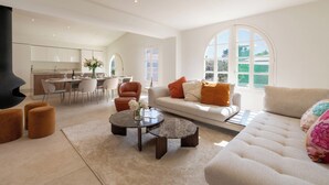 A modern living room with a sofa, coffee table, ottoman, and a fireplace. - 155m² Villa – Sea View & Swimming Pool (Vallauris)