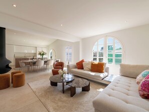 A modern living room with a sofa, coffee table, ottoman, and a fireplace. - 155m² Villa – Sea View & Swimming Pool (Vallauris)