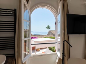 A room with a large window, a television, and a view of the sea. - 155m² Villa – Sea View & Swimming Pool (Vallauris)