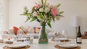 A dining table set with plates, glasses, and a vase of flowers. - 155m² Villa – Sea View & Swimming Pool (Vallauris)
