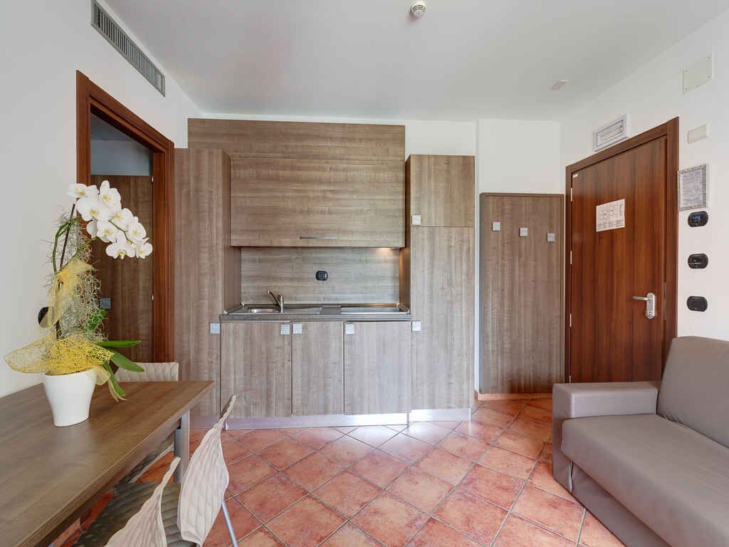 Una cocina compacta con armarios de madera, un lavamanos empotrado y una zona de comedor con mesa y sillas.