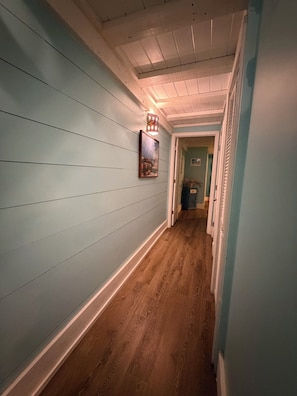 A hallway with light blue walls, wooden flooring, and a framed picture on the wall. - Casa Verano, a cozy 2-bedroom bungalow with loft in charming Panama City Beach! (Panama City Beach)