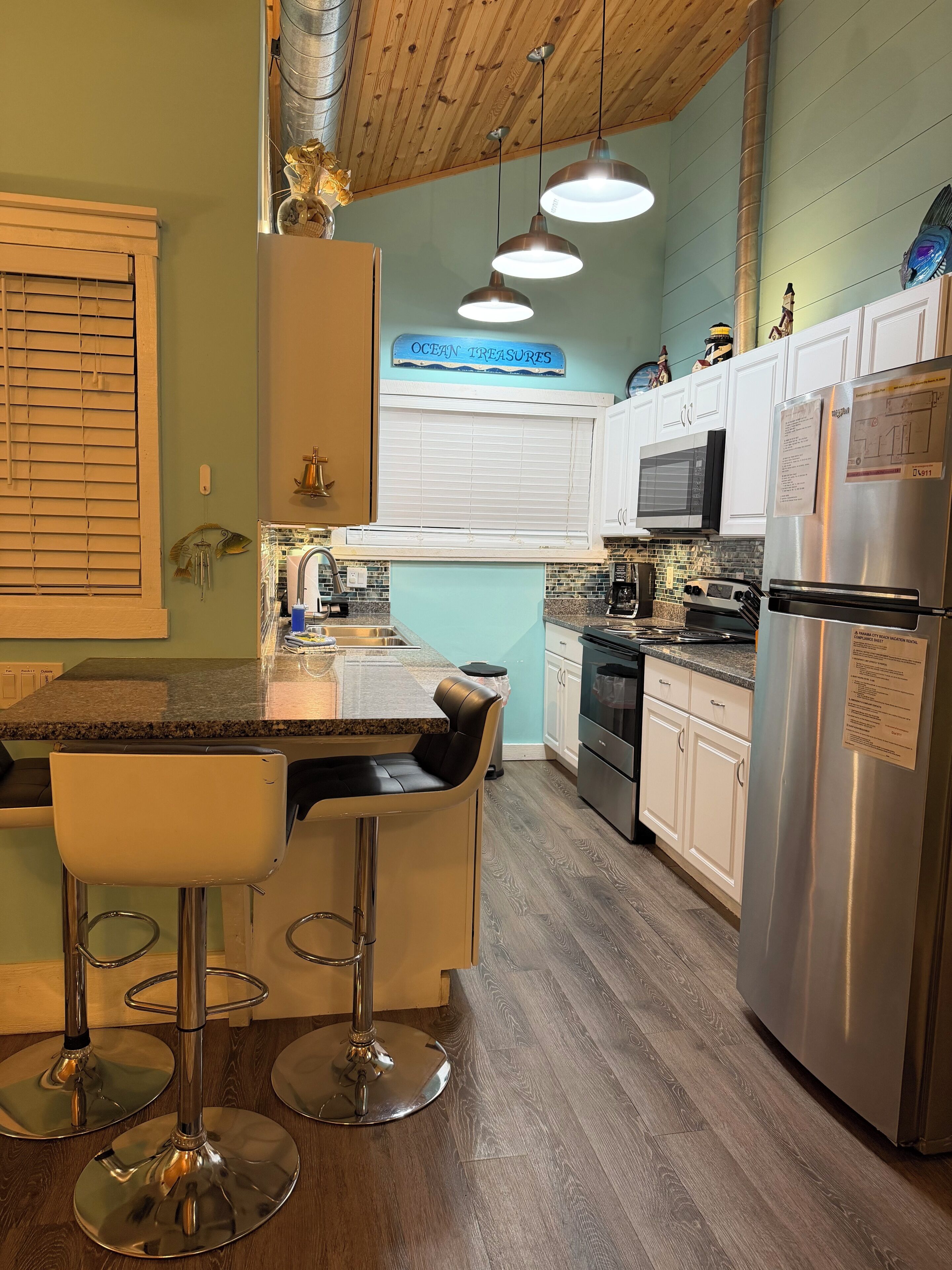 A kitchen with a bar area, stainless steel appliances, and a sign reading 'OCEAN TREASURES'.