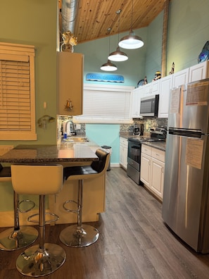 A kitchen with a bar area, stainless steel appliances, and a sign reading 'OCEAN TREASURES'. - Casa Verano, a cozy 2-bedroom bungalow with loft in charming Panama City Beach! (Panama City Beach)