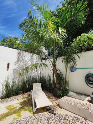 A patio with a white lounge chair, a small table, and a tiled floor. - Beautiful house 5 min from the hotel zone (Cancún)