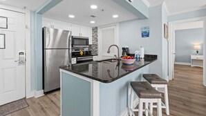 Cozinha moderna com ilha central, eletrodomésticos de aço inoxidável e uma parede com detalhes em azul.