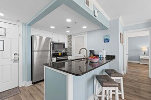 Eine moderne Küche mit Kochinsel, Edelstahlgeräten und einer blauen Akzentwand.