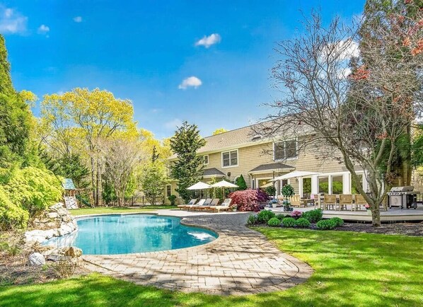 Una propiedad residencial con piscina, mobiliario de patio y una casa grande.