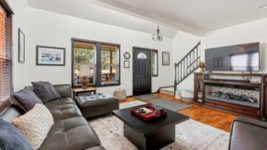 Ein modernes Wohnzimmer mit Sofa, Couchtisch, Kamin und einer Treppe.
