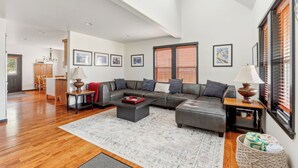 Ein modernes Wohnzimmer mit einem Ecksofa, einem Couchtisch und einem Essbereich mit Holztisch und Stühlen.