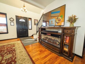 A living room with a fireplace, a television, and a staircase leading to another room.