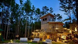 A wooden cabin with a balcony, outdoor seating, and a fire pit.