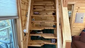 Una scala in legno con vani contenitori integrati, una finestra a sinistra e un tappeto decorativo sul pavimento.