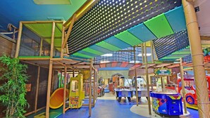 Ein Indoor-Spielbereich mit Klettergerüsten, Rutschen und Spielautomaten.