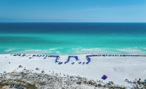 Una playa con vista despejada al océano y una zona arenosa con sombrillas.