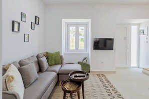 A living room with a sofa, a coffee table, a patterned rug, a television, and framed pictures on the wall. - Green Near The Sea, By Home Match (Setúbal)