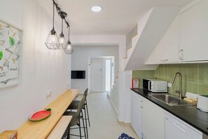 A modern kitchen with a wooden dining table, a microwave, and a sink. - Green Near The Sea, By Home Match (Setúbal)