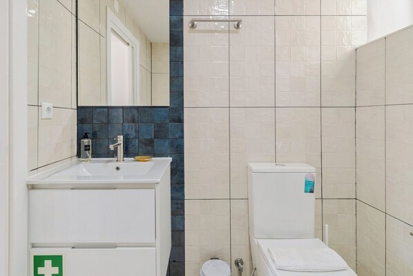 Une salle de bain avec un lavabo blanc, un miroir et des toilettes.