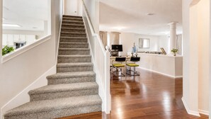 Una escalera que lleva a una sala de estar con una cocina al fondo.