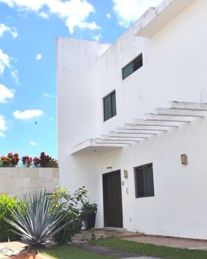 A modern two-story building with a flat roof, a central staircase, and a small window on the upper floor. - Luxury house with pool (Cancún)