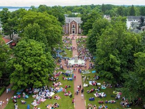 An outdoor gathering with a central walkway, surrounded by trees and buildings.