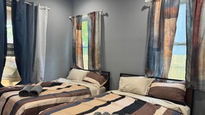 Ein Schlafzimmer mit zwei Betten, einem Fenster mit Vorhängen und zusammengerollten Handtüchern auf dem Bett.
