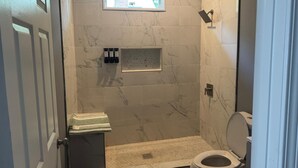 Ein kleines Badezimmer mit Toilette, Dusche und einer kleinen Ablage für Toilettenartikel.