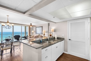 A kitchen with a large island, a dining area with chairs, a ceiling fan, and a view of the ocean. - Free beach chairs!!! LONG BEACH one bedroom!! Great views! (Panama City Beach)