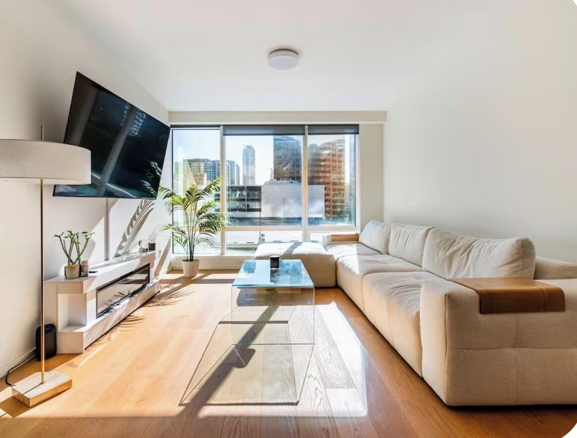 Una sala de estar moderna con sofá, mesa de centro, televisor y chimenea.