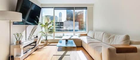Una sala de estar moderna con sofá, mesa de centro, televisor y chimenea.